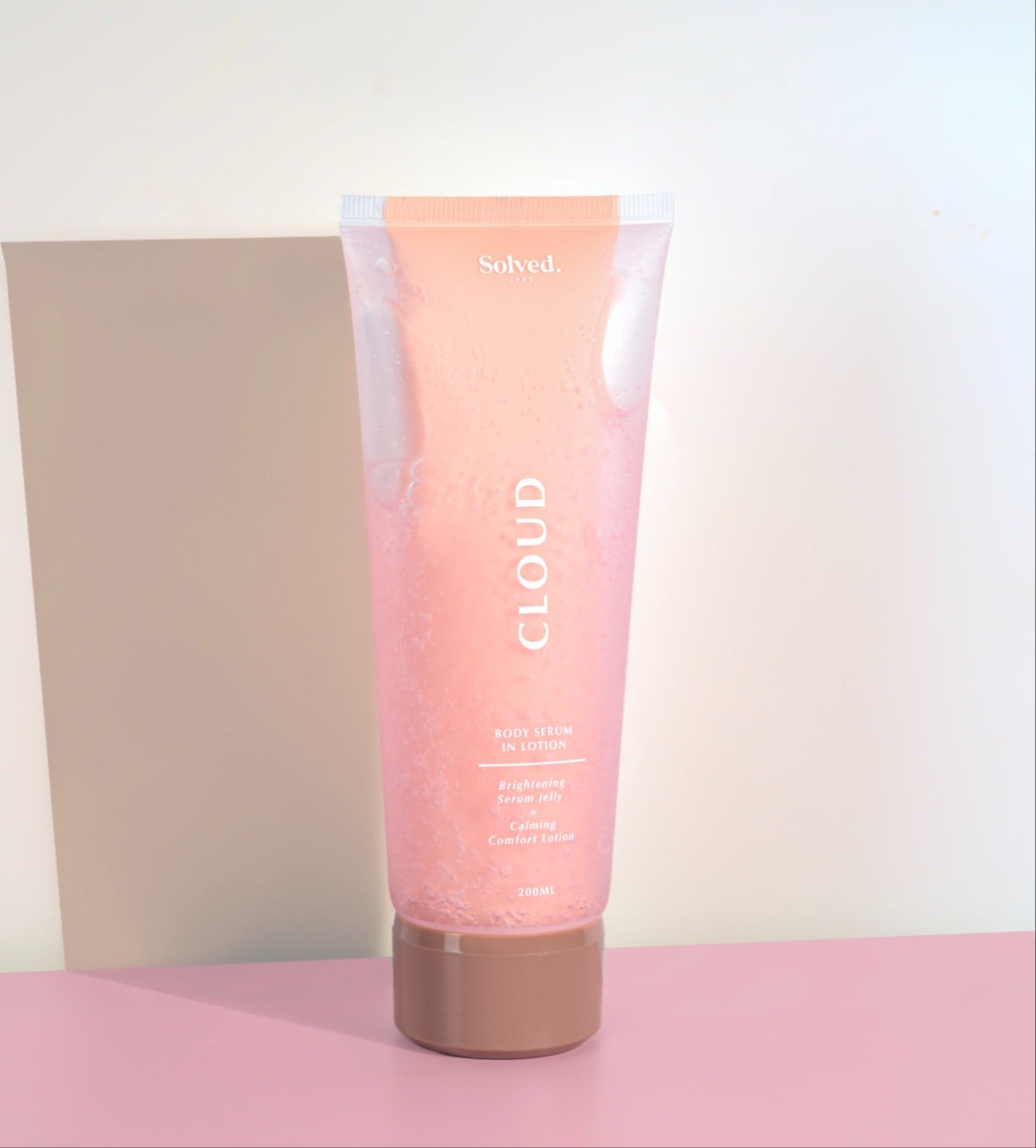Pink body lotion tube of cream with 'Solved' branding on a pink background